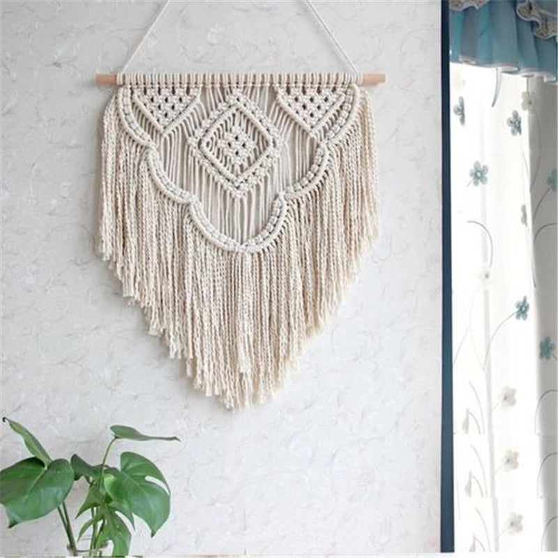 a macrame hanging on a wall next to a potted plant