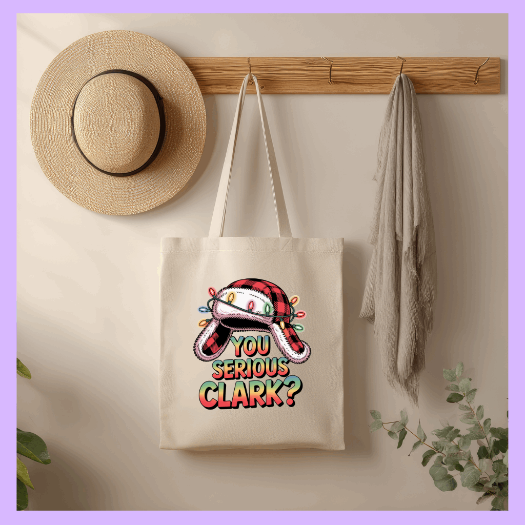 Tote bag with Christmas-themed design hanging on a wall with a hat and towel.