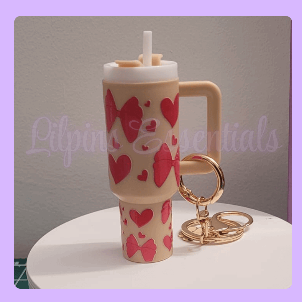 Beige tumbler with red heart and bow designs, gold keychain