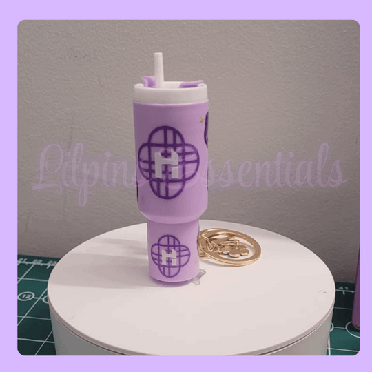 Purple tumbler keychain with a straw on a white stand a