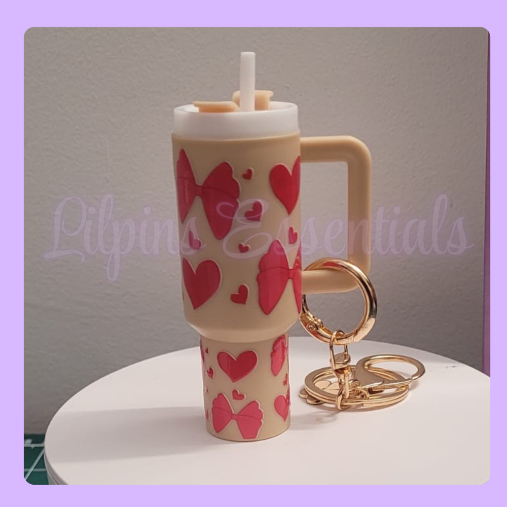 Beige tumbler with red heart and bow designs, gold keychain