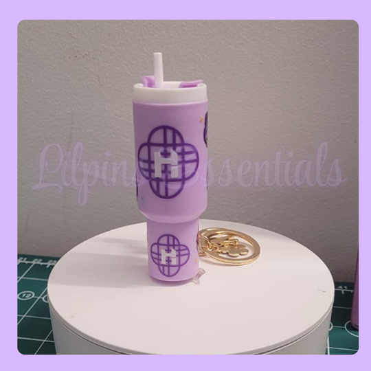 Purple tumbler keychain with a straw on a white stand a