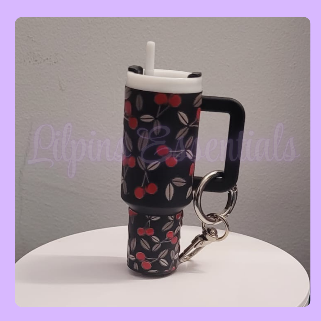 Miniature cup with cherry pattern and keychain on a gray background