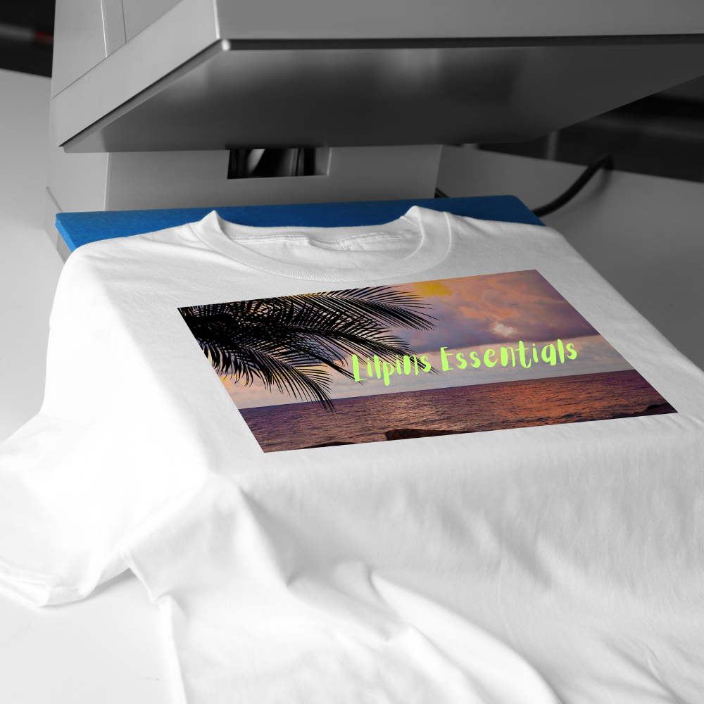 White t-shirt with a printed design of a palm tree and 'Lilpins Essentials' text, being printed on a heat press machine.